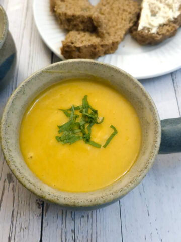Close up of a bowl of spicy butternut soup garnished with chopped parsley.