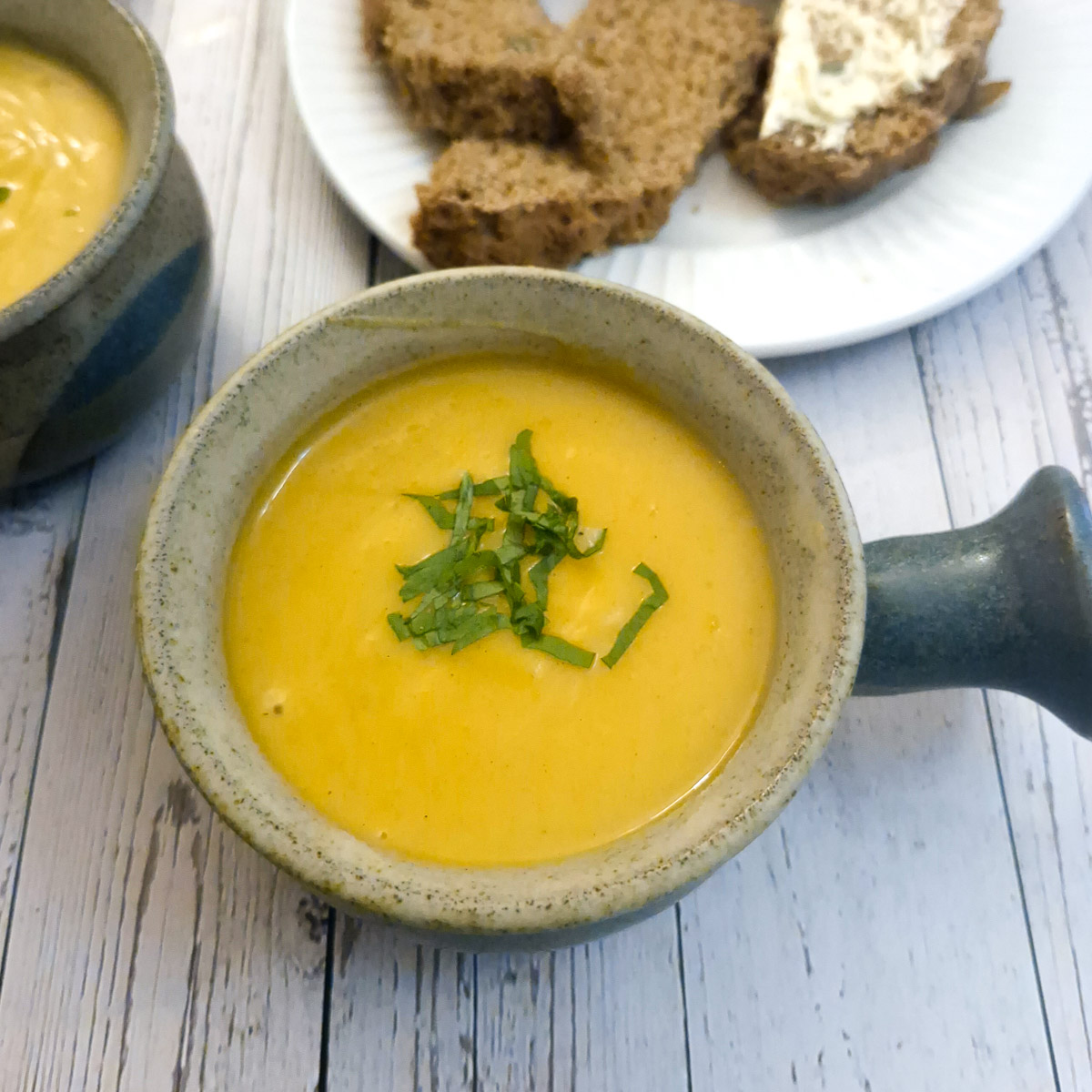 Close up of a bowl of spicy butternut soup garnished with chopped parsley.