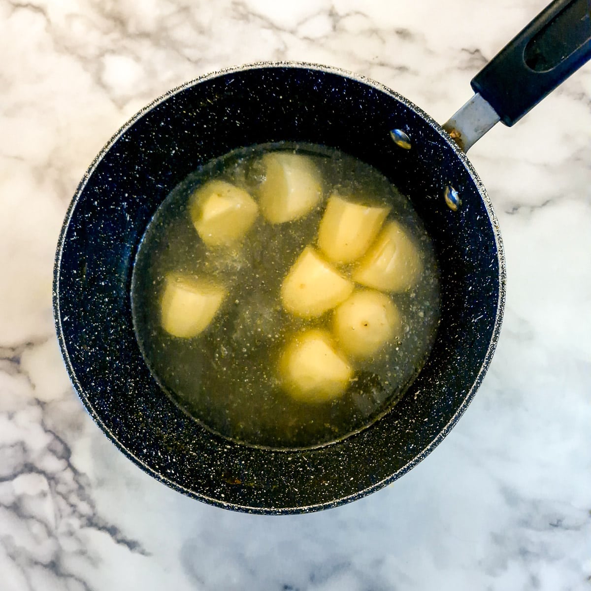Potatoes in stock in a saucepan.