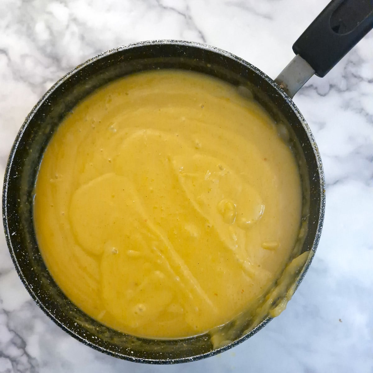 Blended butternut soup in a saucepa.