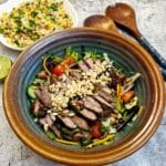 A serving dish of Thai beef salad garnished with chopped peanuts.