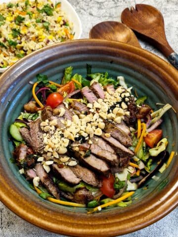 A serving dish of Thai beef salad garnished with chopped peanuts.