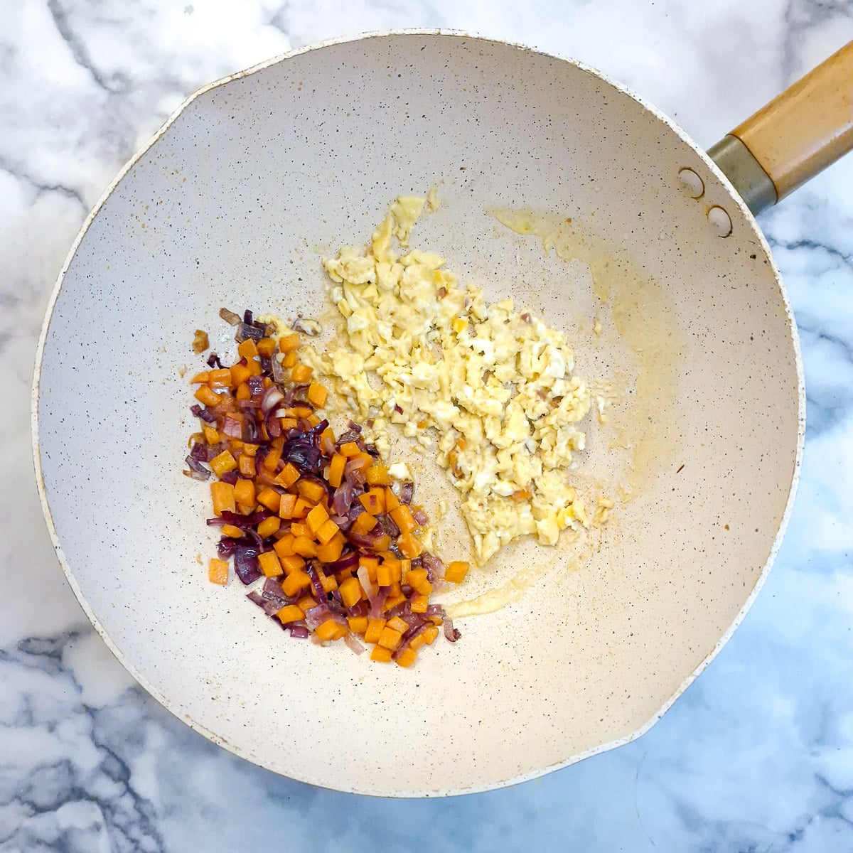 Scrambled egg with carrots and onions in a wok.