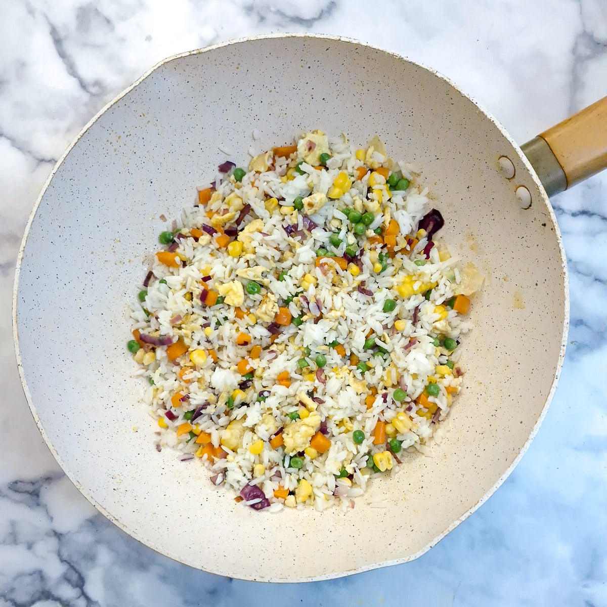 Rice, peas and corn added to the wok.
