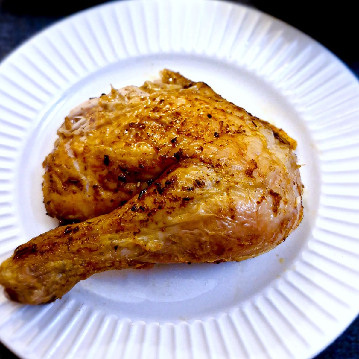 A cooked chicken leg on a white plate.
