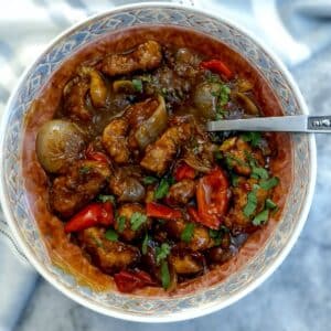 A serving dish of crispy orange pork stir fry.