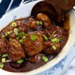 A dish of sticky chicken meatballs with a large wooden serving spoon,