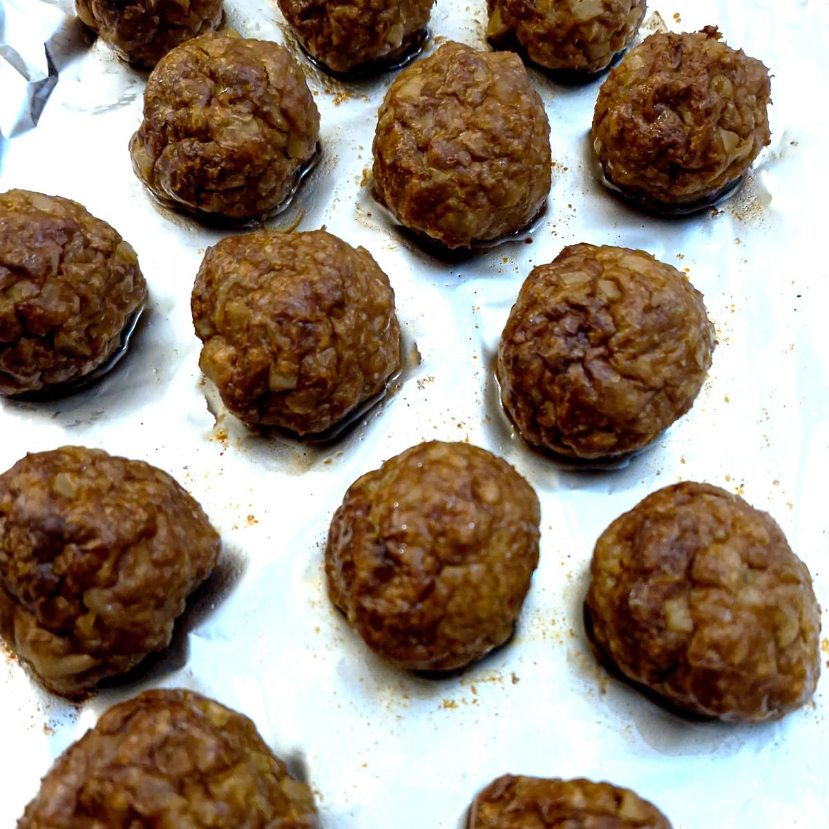 Close up of cooked meatballs on a baking tray.