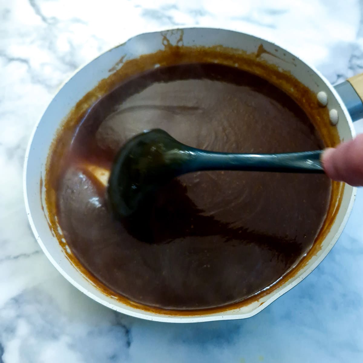 Cooked sauce with a spoon showing the thick consistency.