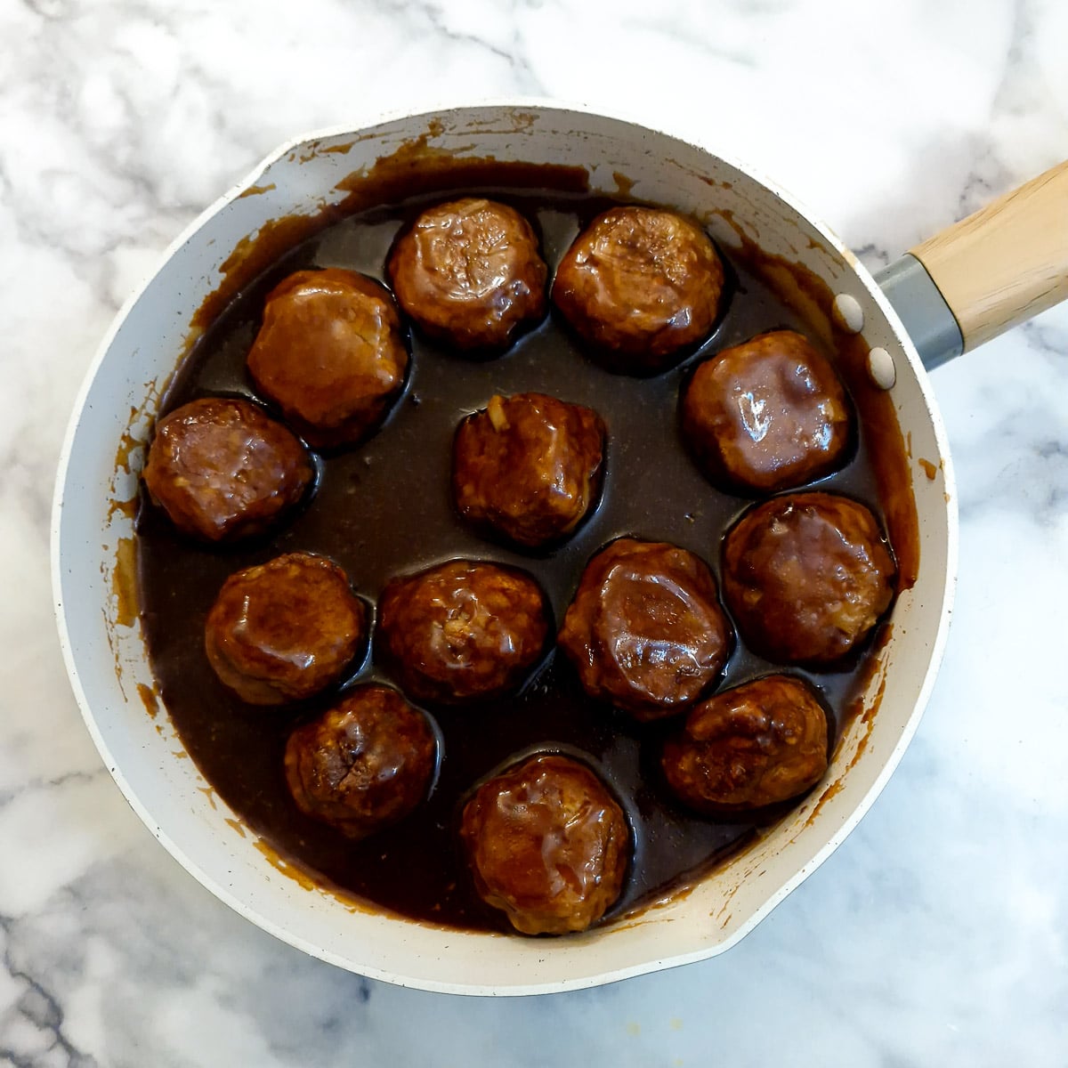 Meatballs combined with sauce in a frying pan.