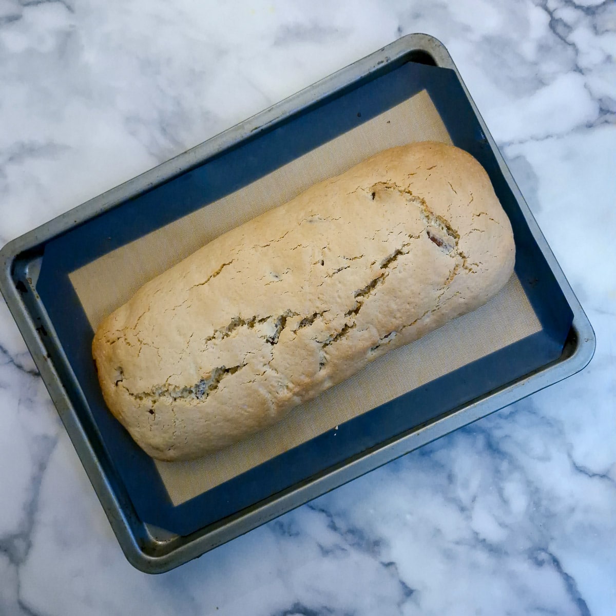 A log of baked biscotti on a baking sheet.