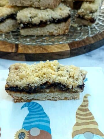 A slice of mince pie crumble of a serviette decorated with three gnomes.