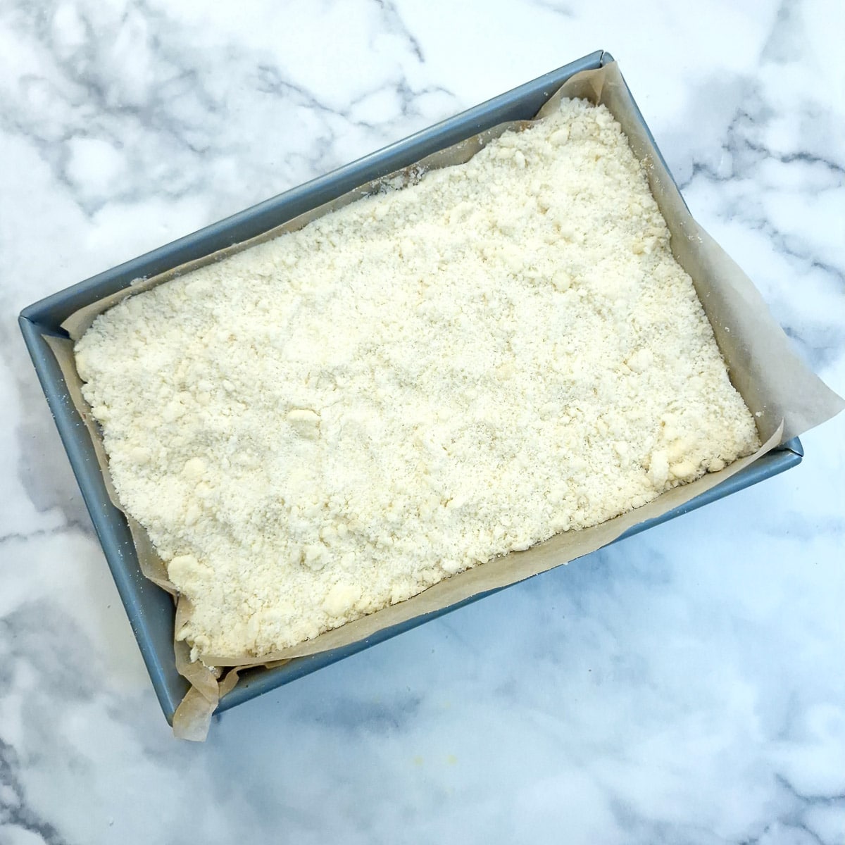 Crumble mixture spread over the fruit mince in a baking tray.