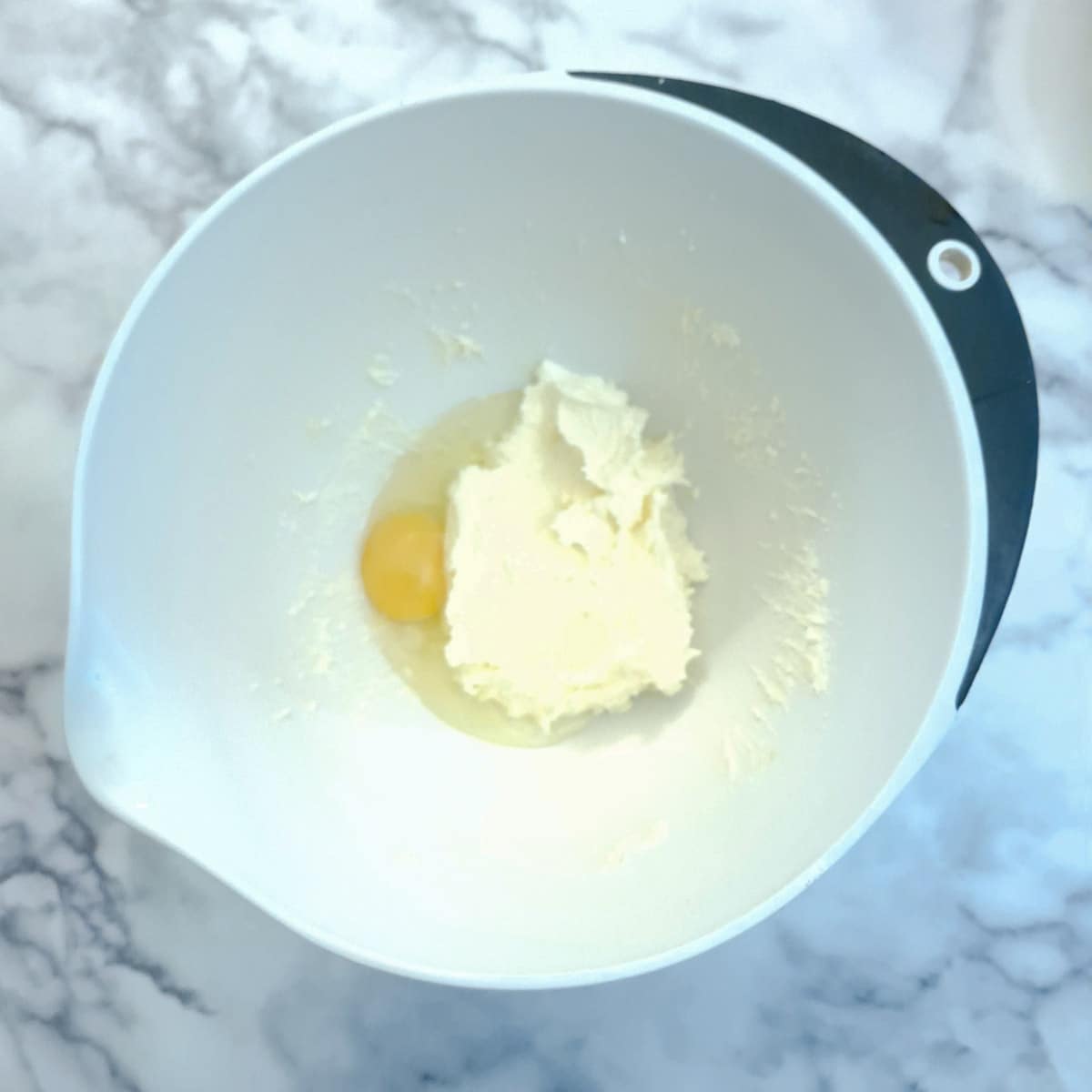 Creamed butter and sugar in a mixing bowl with an egg.
