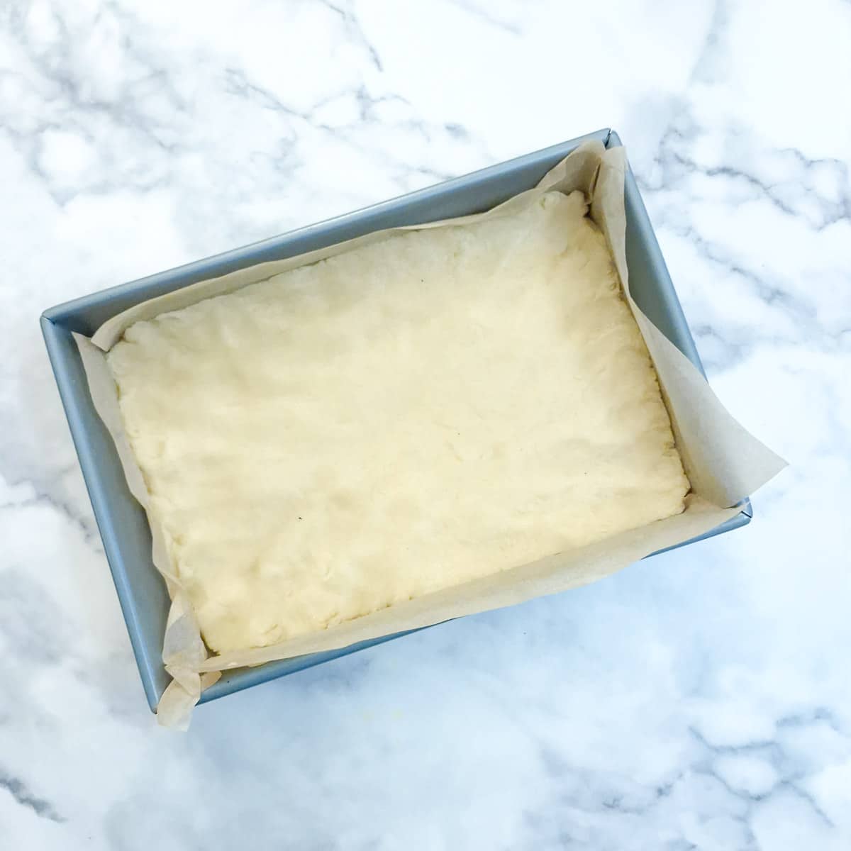 Dough pressed into a lined baking tin.