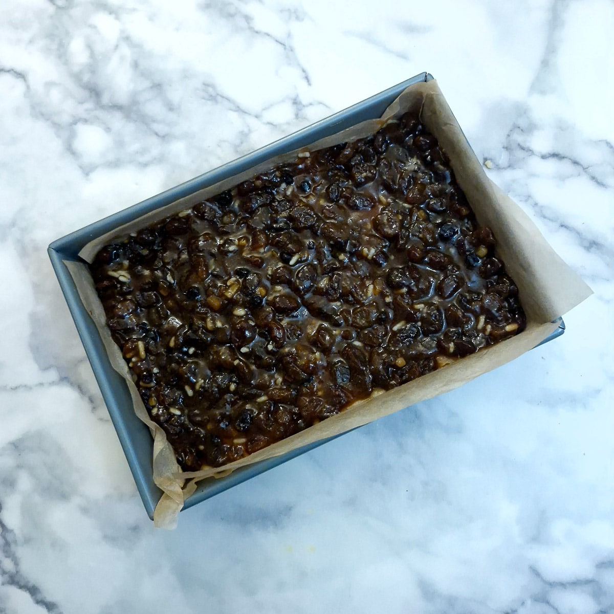 Fruit mincemeat spread onto dough in a baking tin.