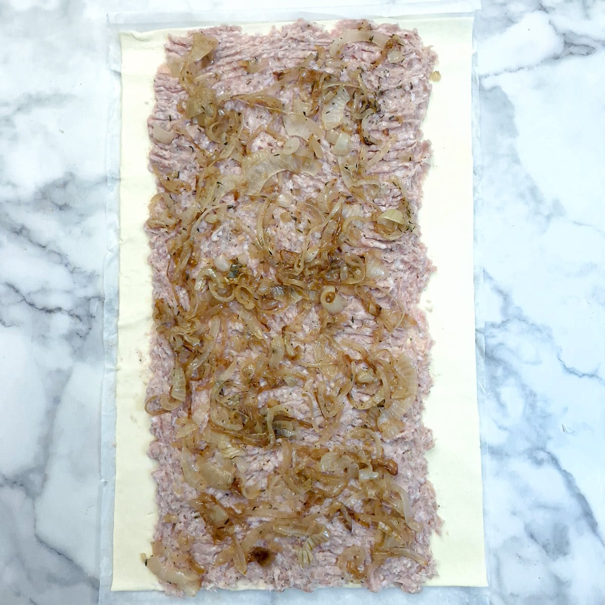 Caramelised onions spread onto the sausage meat.