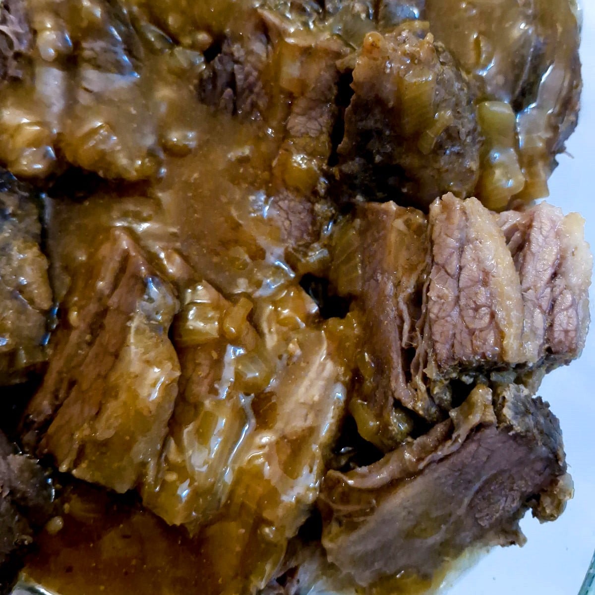 Close up of sliced brisket smothered in onion gravy.
