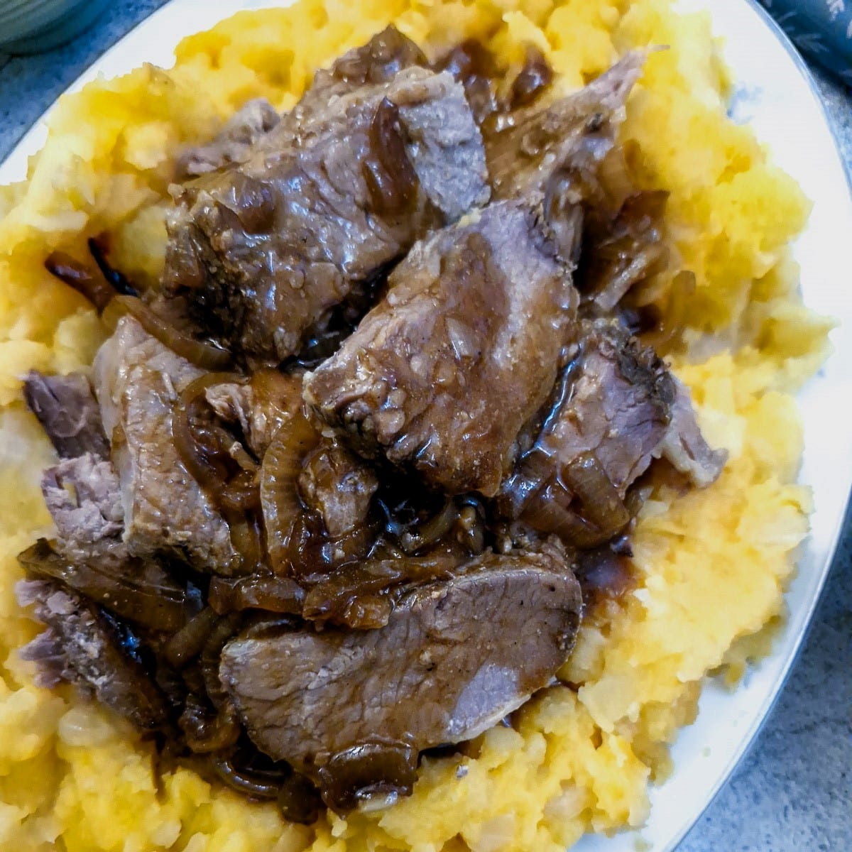Close up of slow cooker brisket on a pile of root vegetable mash.