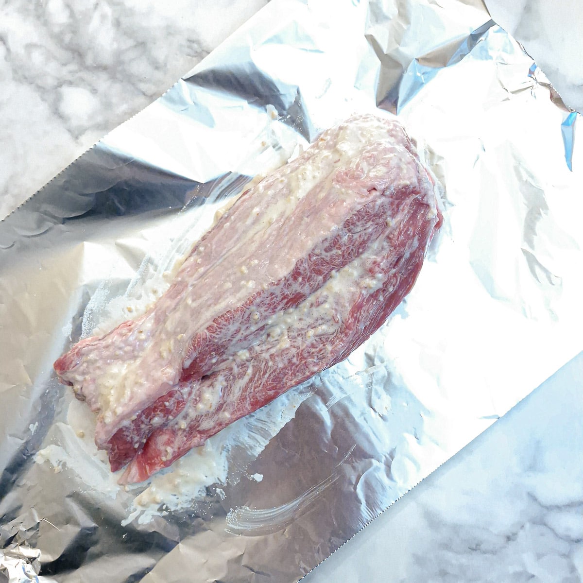 A piece of unrolled brisket coated in creamed horseradish.