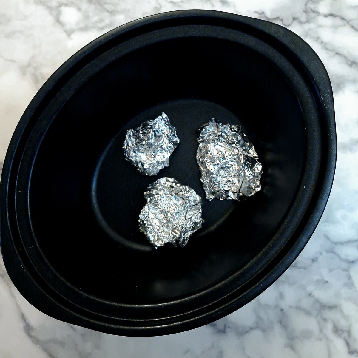 Three balls of tin foil in the base of a slow cooker.