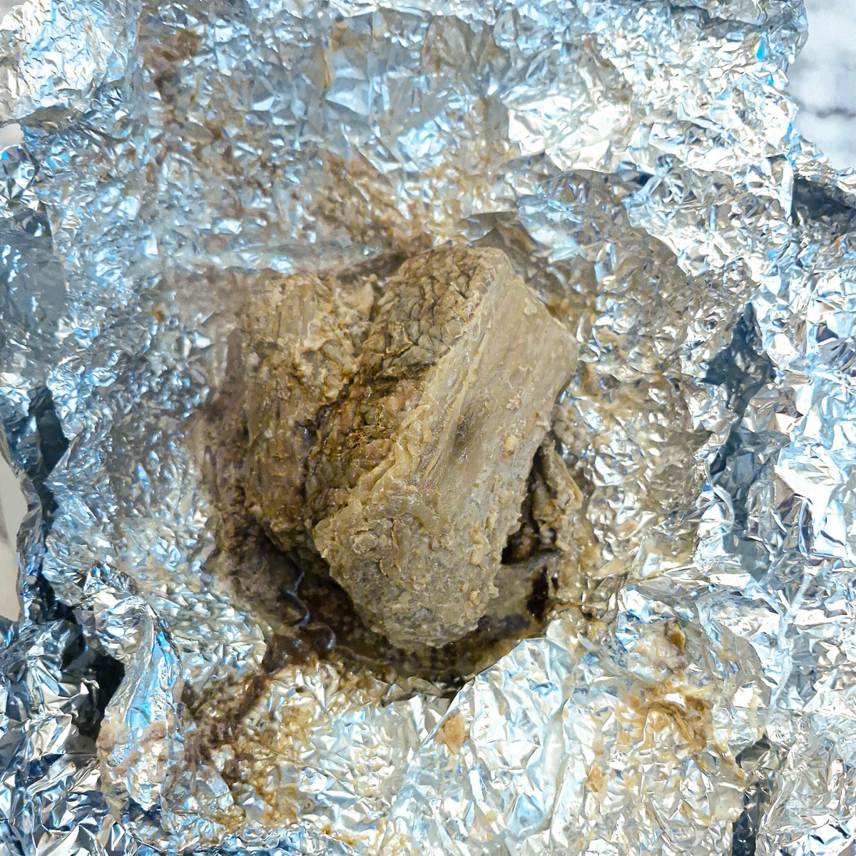 Cooked brisket unwrapped on a sheet of tin foil.