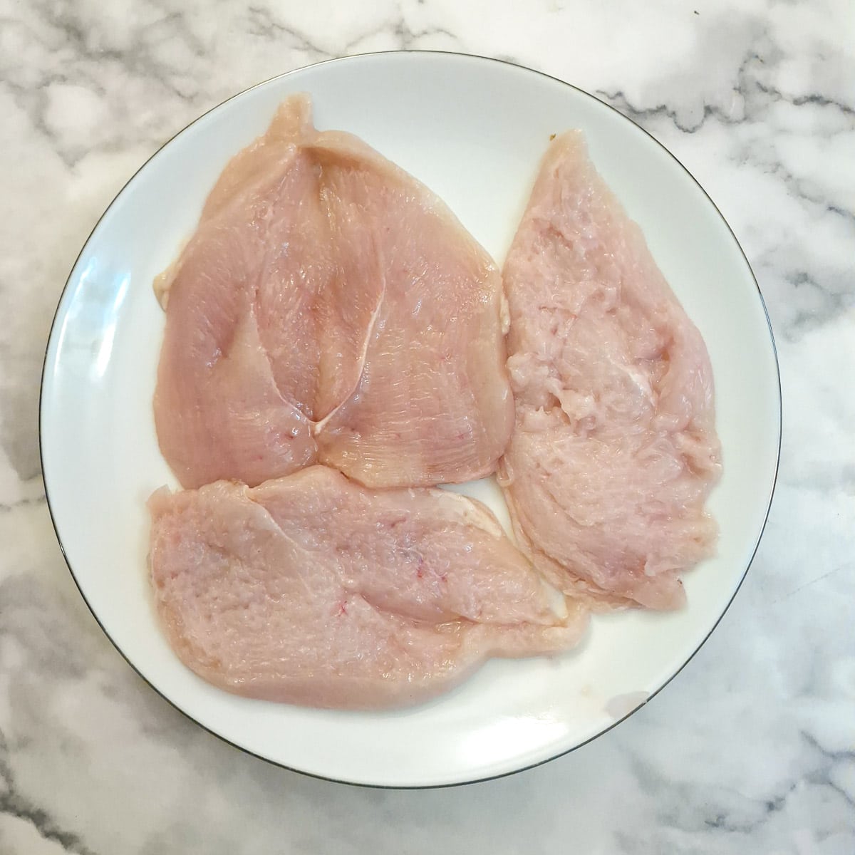 Raw  chicken schnitzels on a plate.