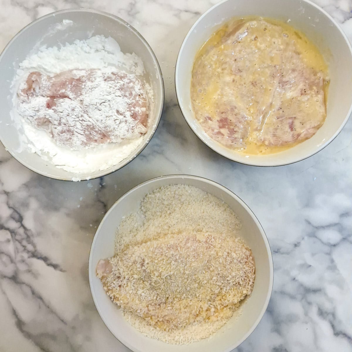 Chicken schnitzels being crumbed.