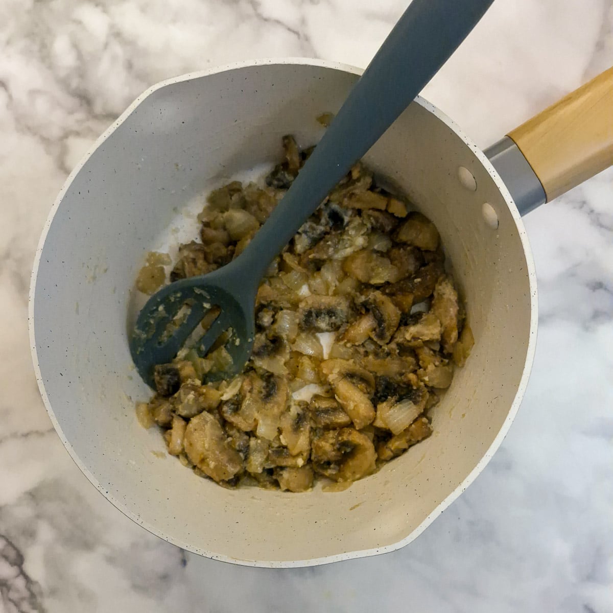 Flour added to mushrooms and onions in a saucepan.