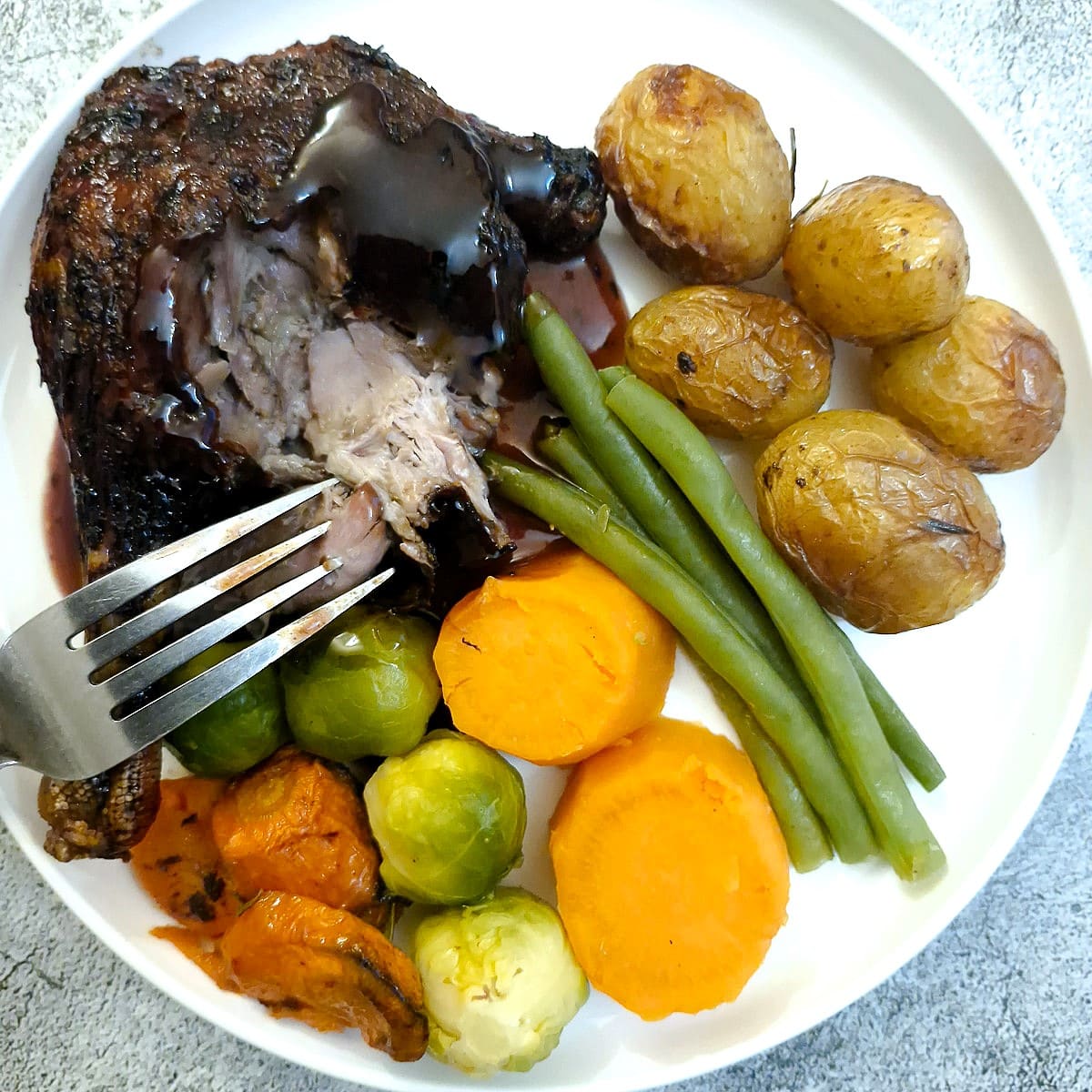 Close up of a roast duck leg which has been cut open to show the meat inside.