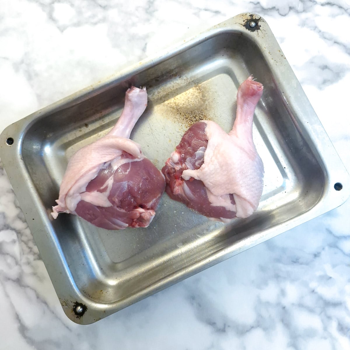 Two duck legs in a roasting tray.