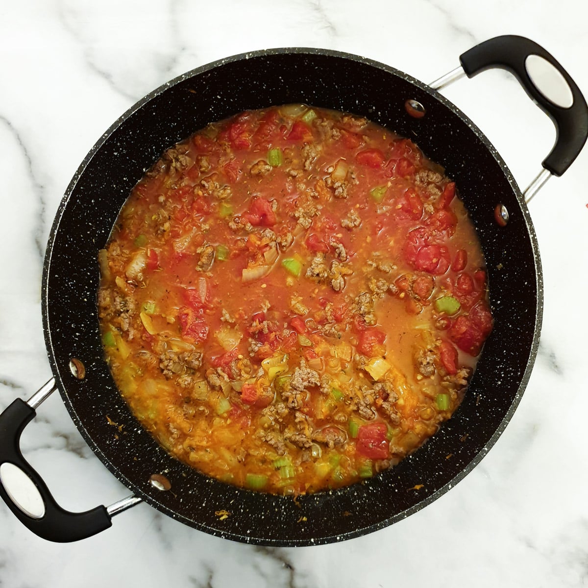 Tomatoes, fried beef and stock added to the frying pan to simmer for the meat sauce.