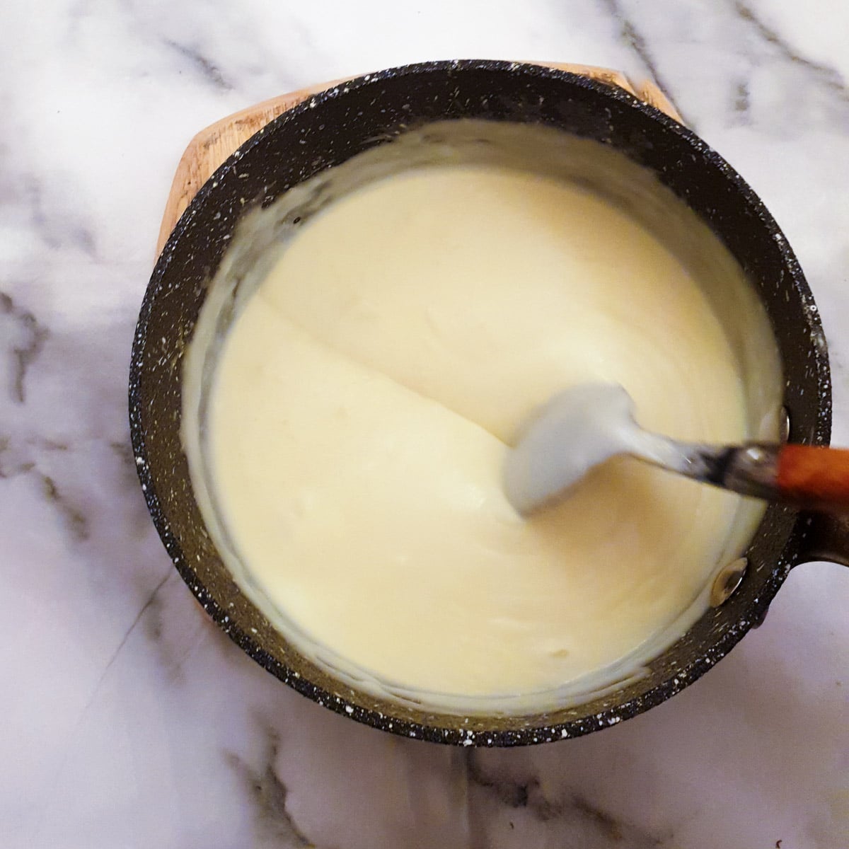 A saucepan of thickened bechamel sauce.