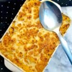 A serving dish of haddock au gratin with a serving spoon on top.