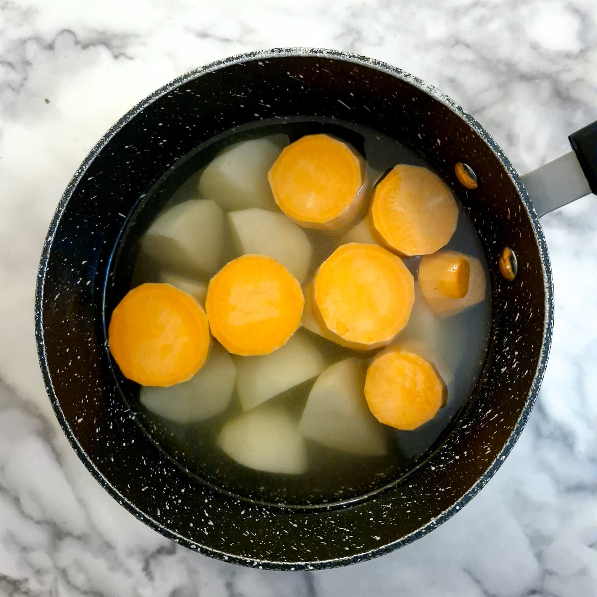 Sweet potatoes and potatoes in a saucepan of water.