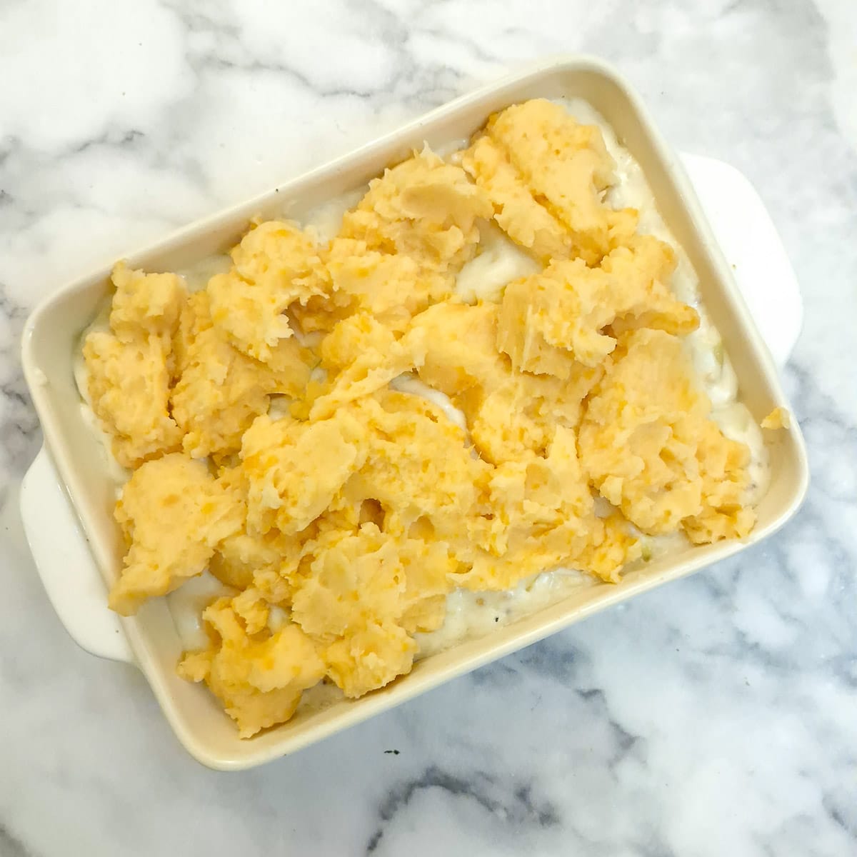 Spoonfuls of sweet potato mach on top of bechamel sauce.