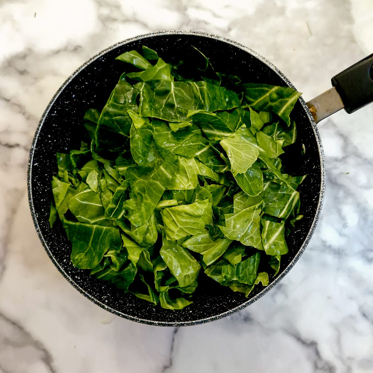 A saucepan filled with chopped spring greens.