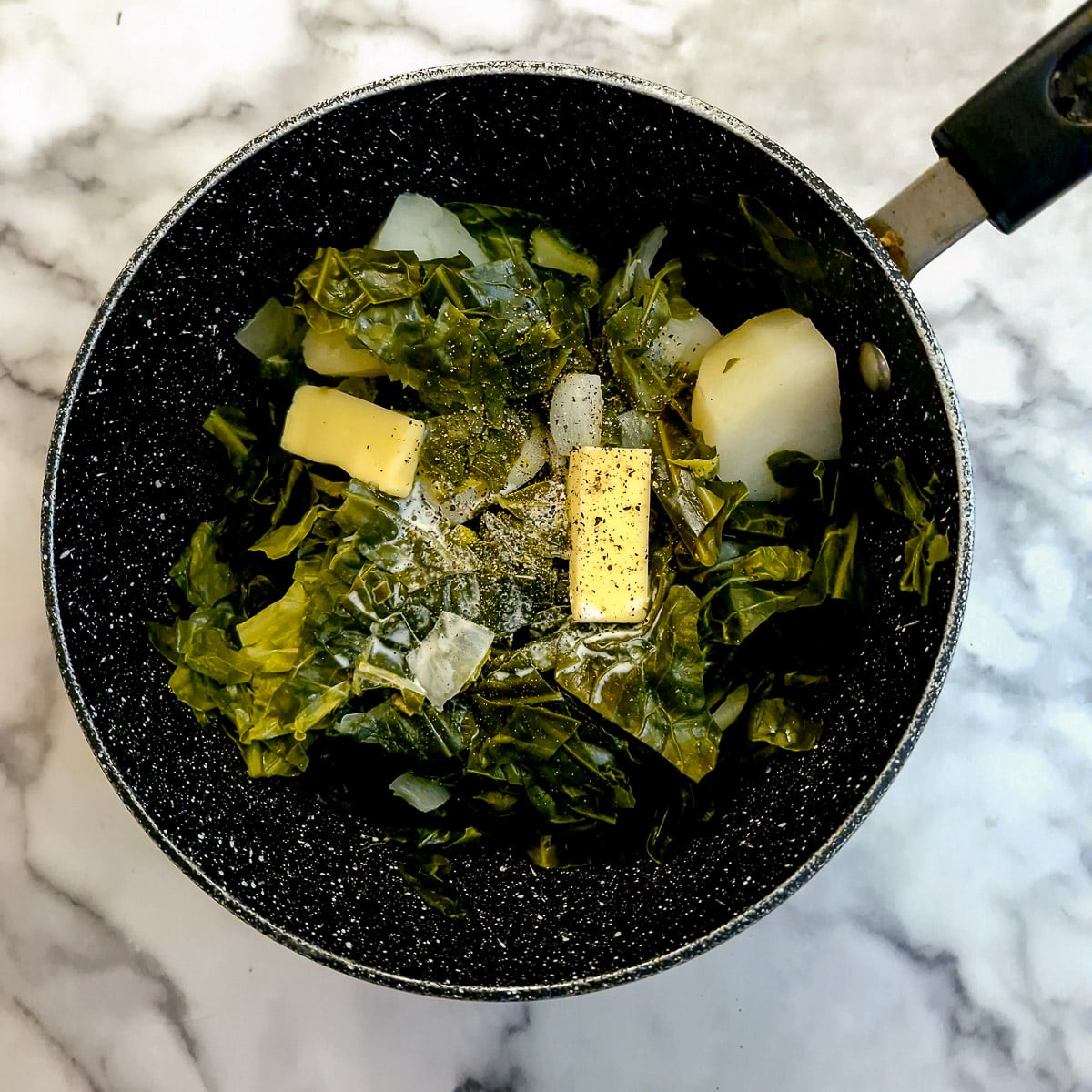 Butter and cream added to a saucepan of drained spring greens, potatoes and onions.