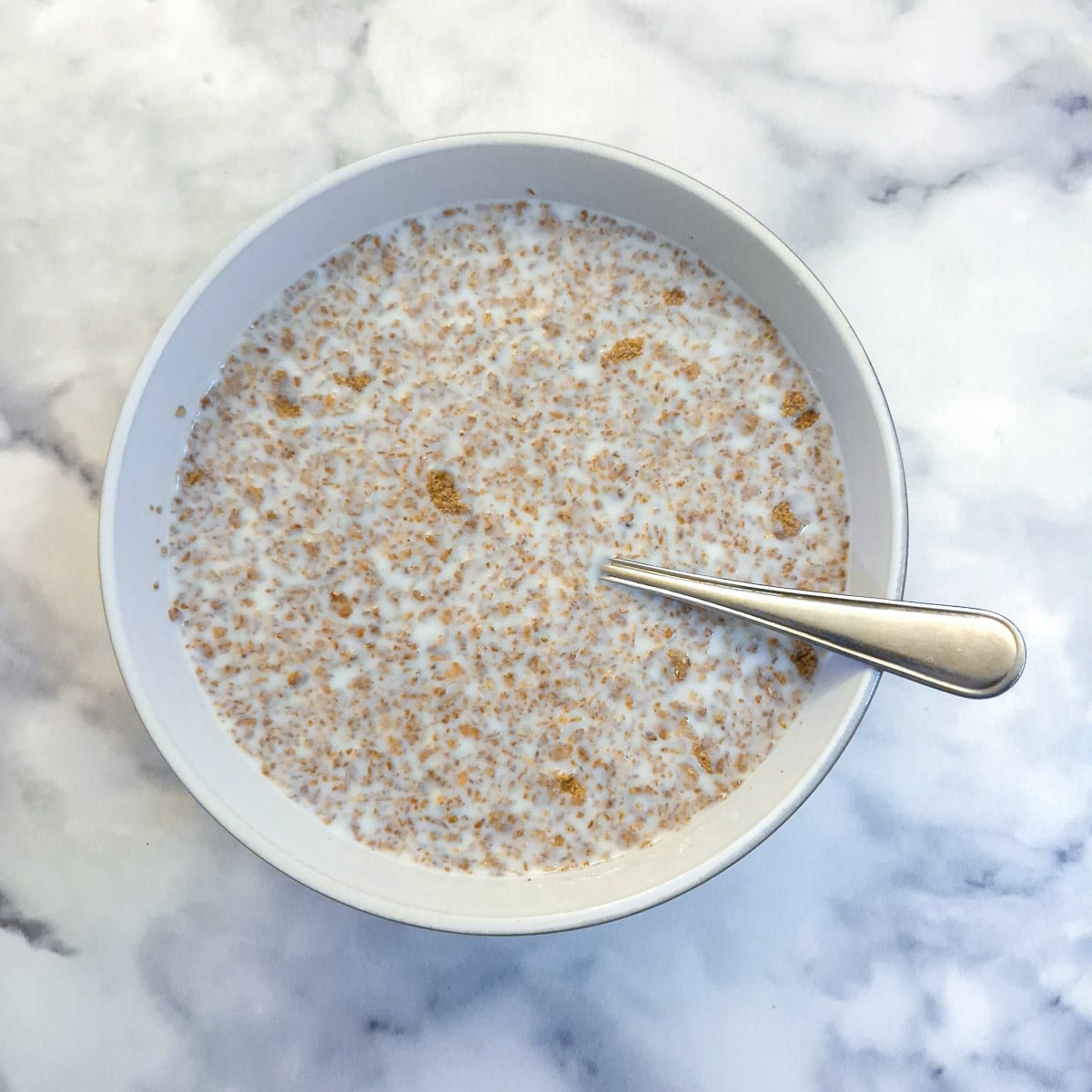 Crushed bran flakes softening in a bowl of milk.