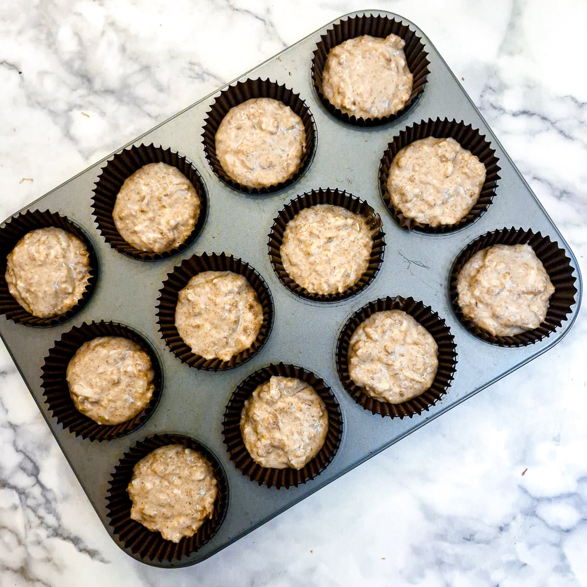 12 unbaked muffins in a tray.