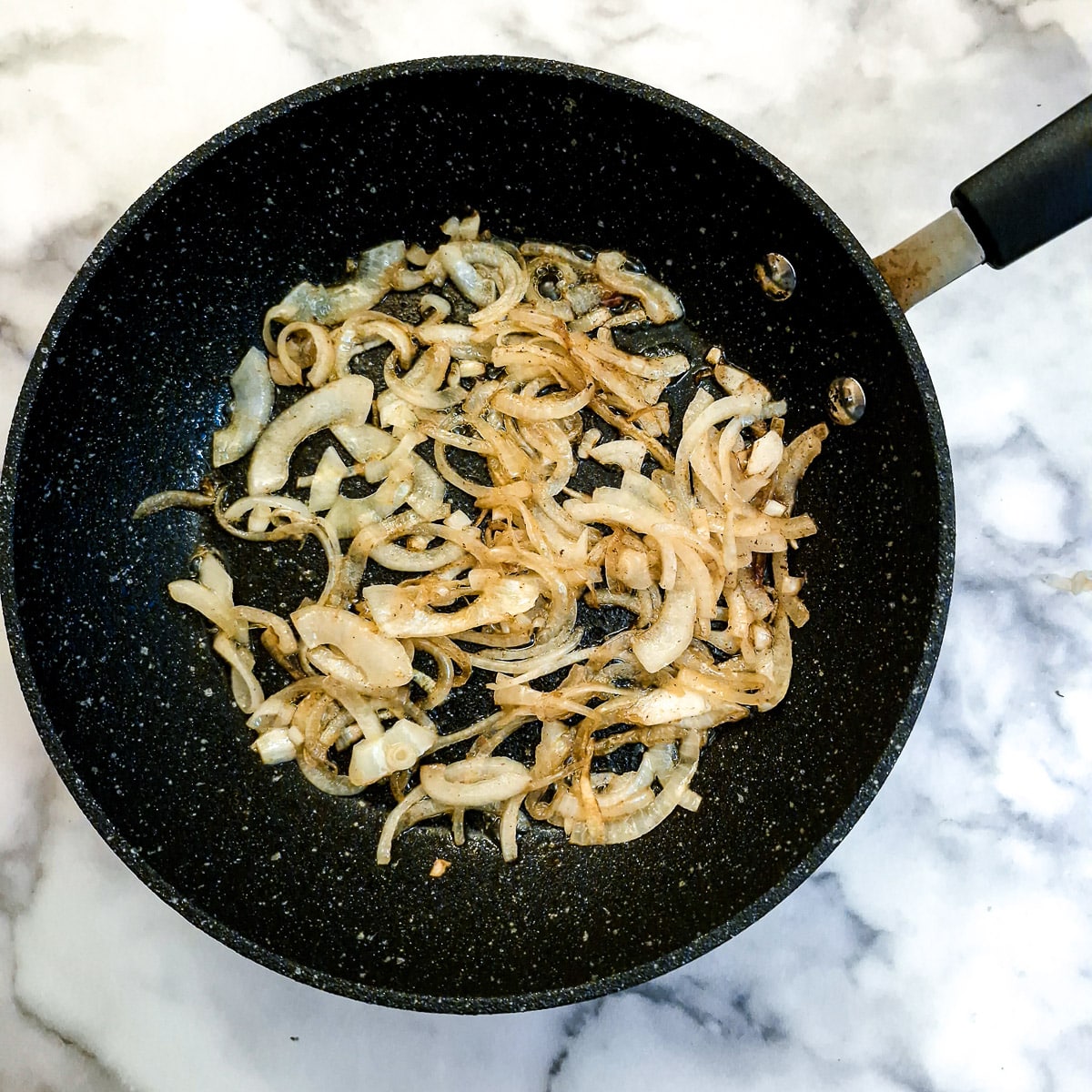 Onions caramelising in a frying pan.