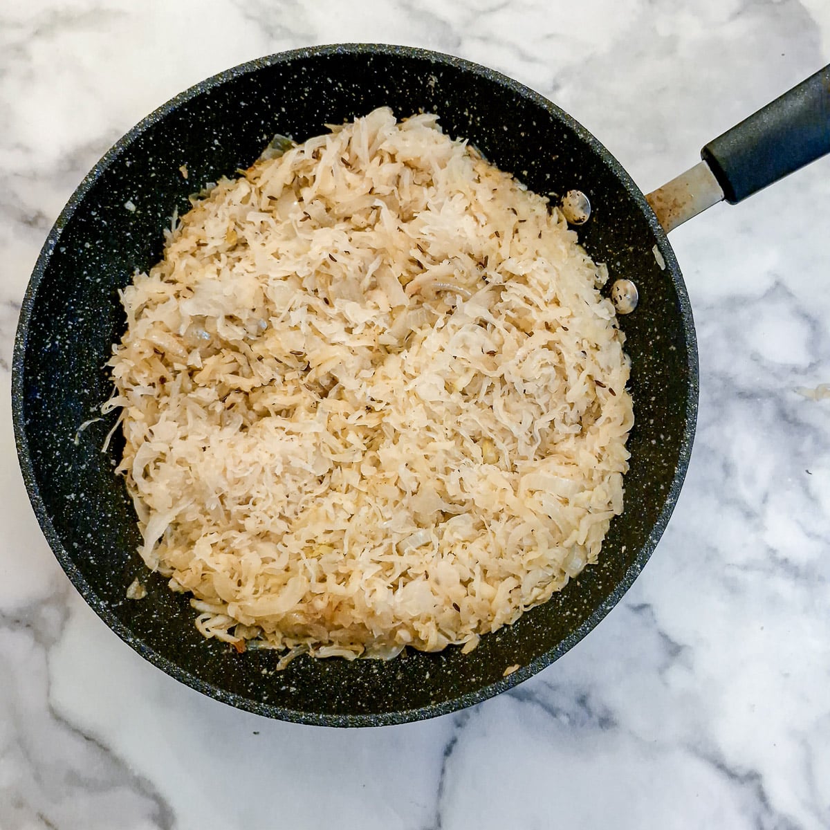 Sauerkraut combined with apples and onions in a frying pan,