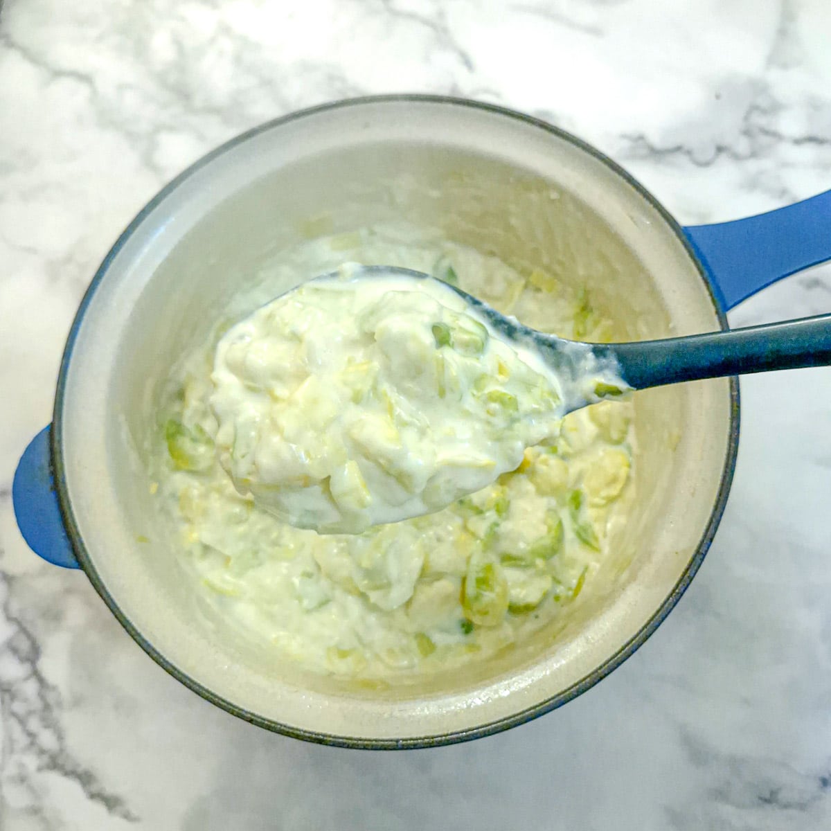 Leeks and brussels sprouts in a thick bechamel sauce in a saucepan.