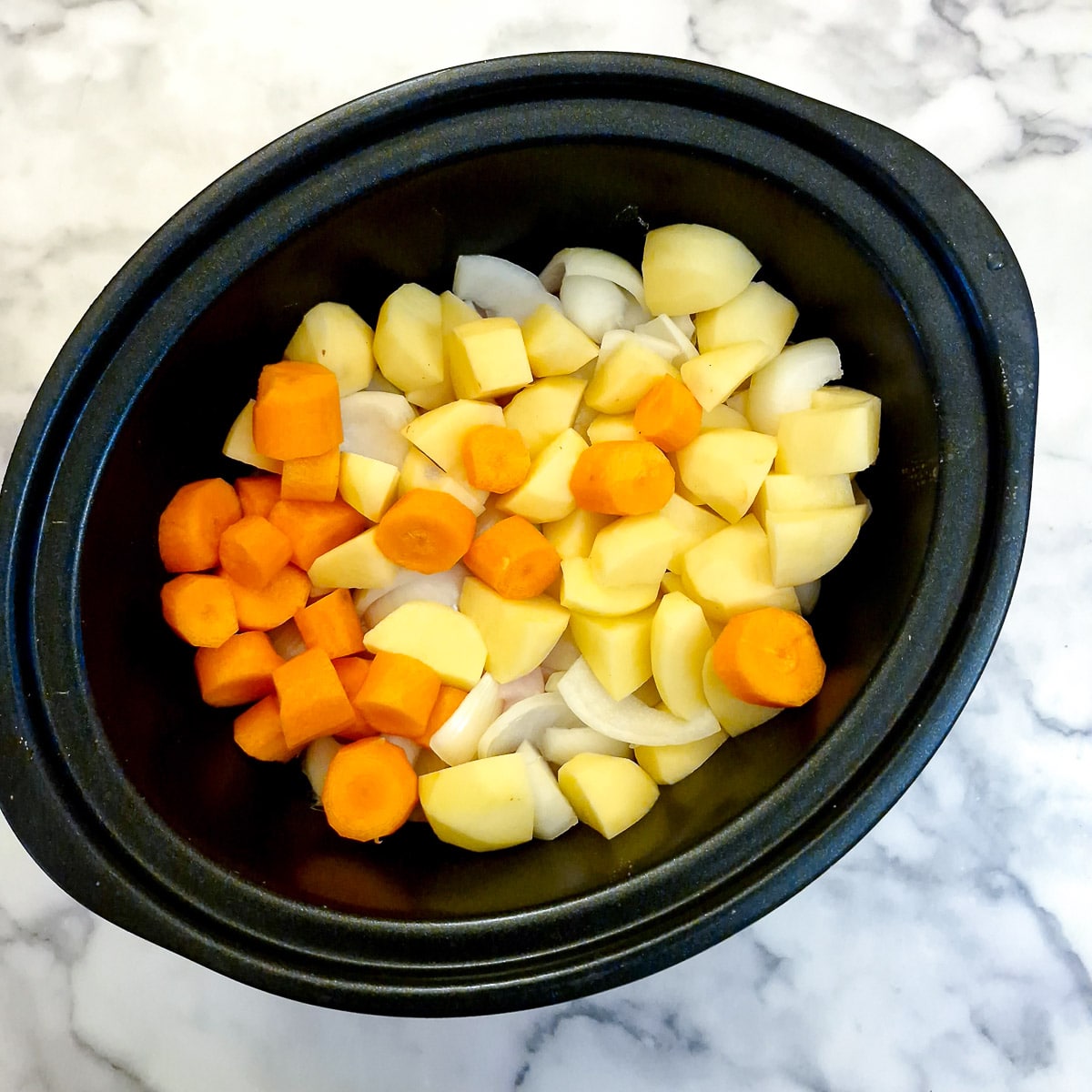 Vegetables added to chicken in a slow cooker.