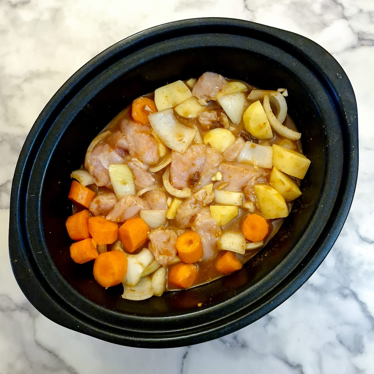 Stock, chutney, passata and spices poured over veggies and chicken in a slow cooker