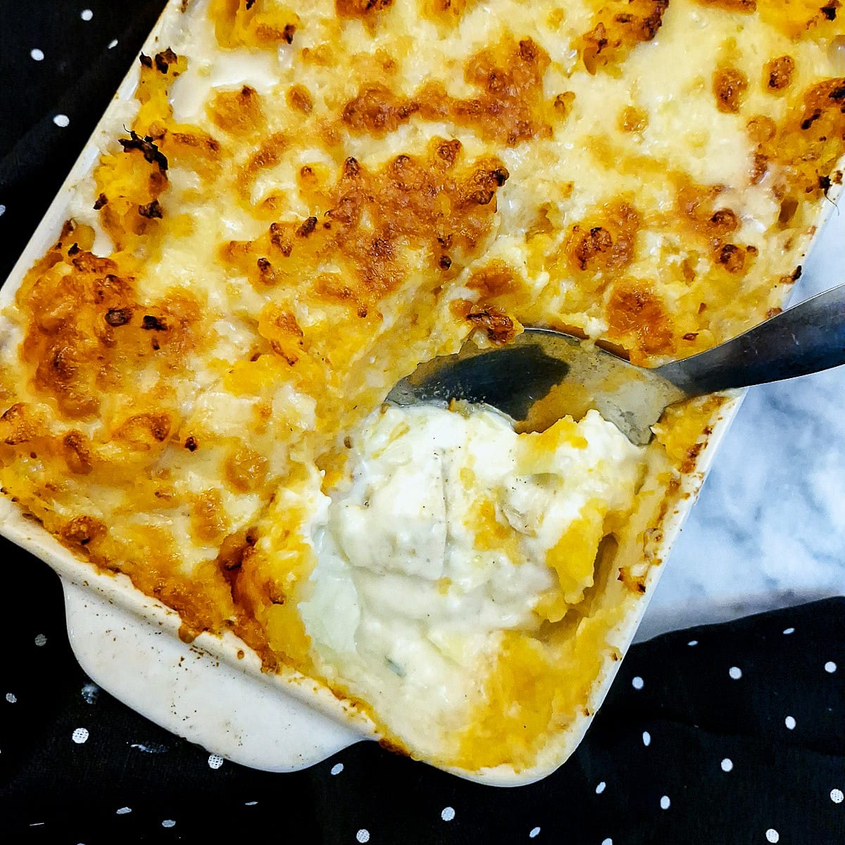 Overhead shot of haddock au gratin with some of the potato mash removed to show the fish below.