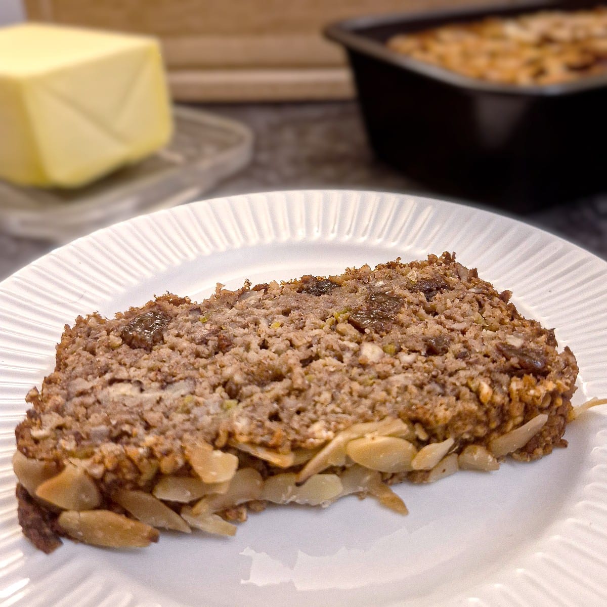 A slice of honey oat apple and banana bread on a white plate.