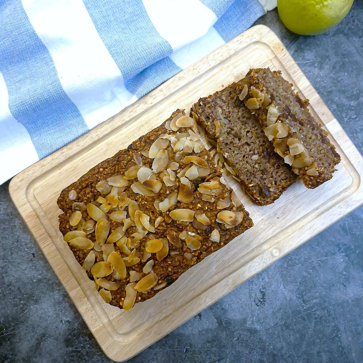 Overhead shot of the honey oat bread on a wooden plank with 2 slices in front.
