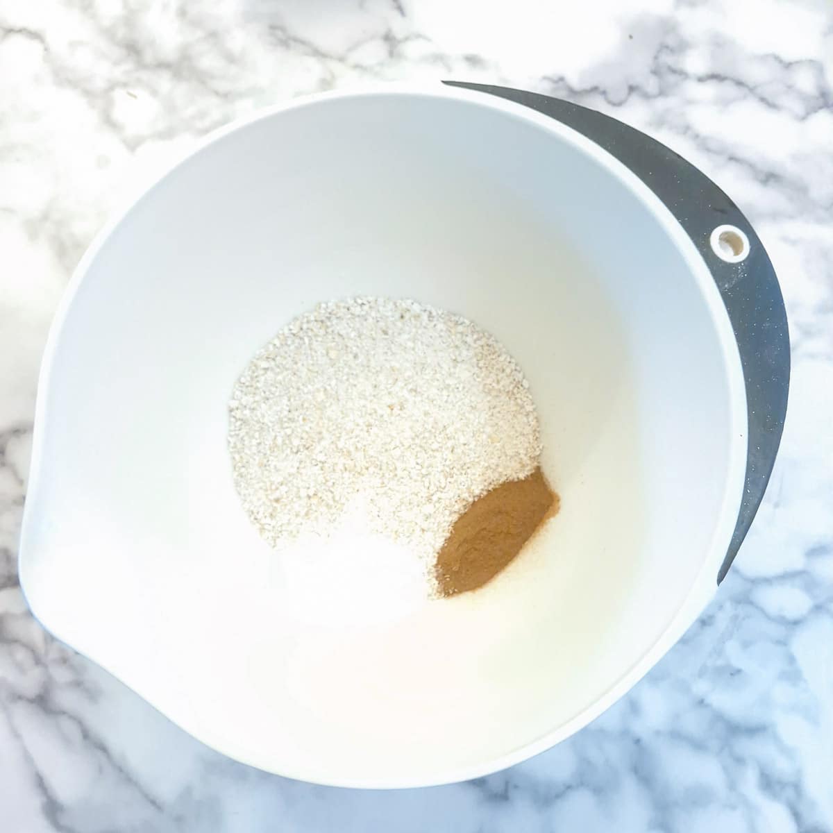 Oat flour, baking powder and spices in a mixing bowl.