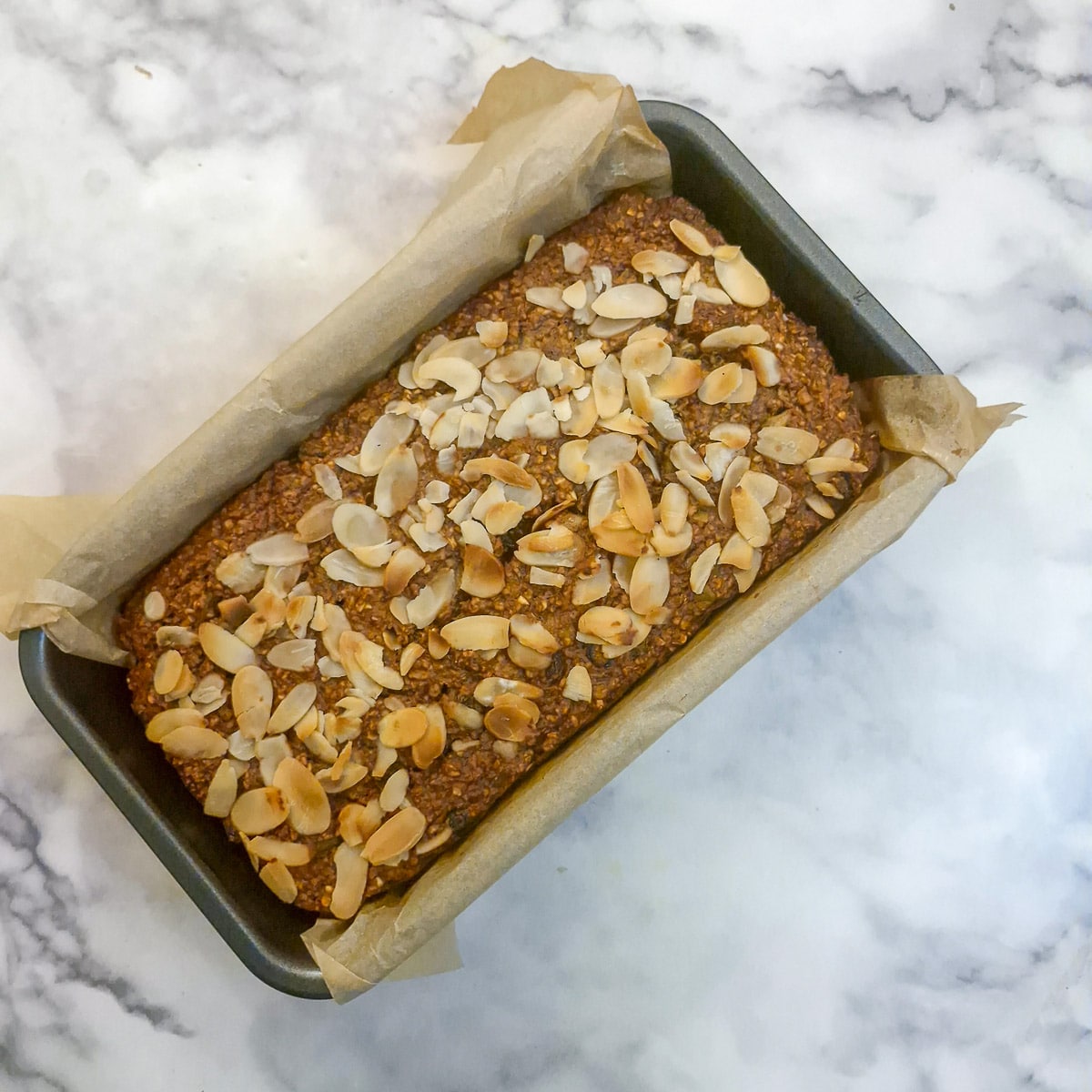 A cooked honey oat loaf in a baking dish.